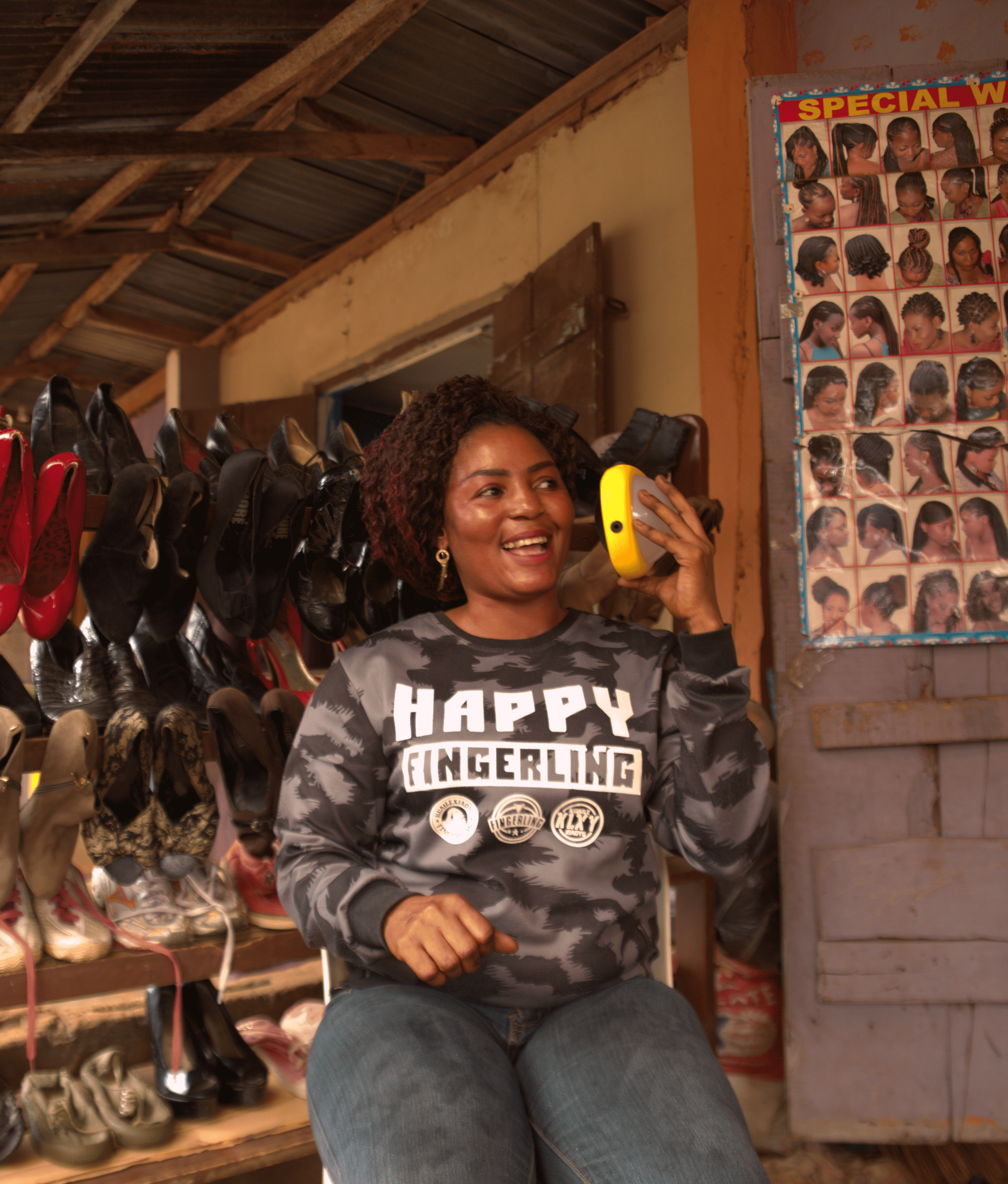 Woman listening to her solar powered Sun King Boom outside her store.